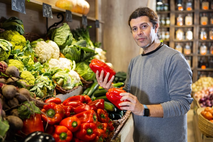 Man holding red bell peppers in the grocery store