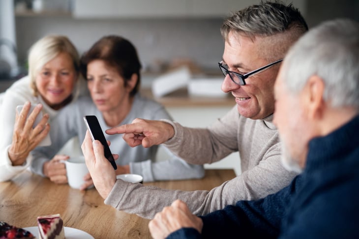 Senior friends look at pictures on smartphones