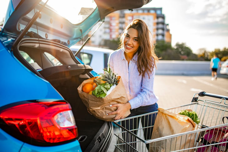 woman putting groceries in car