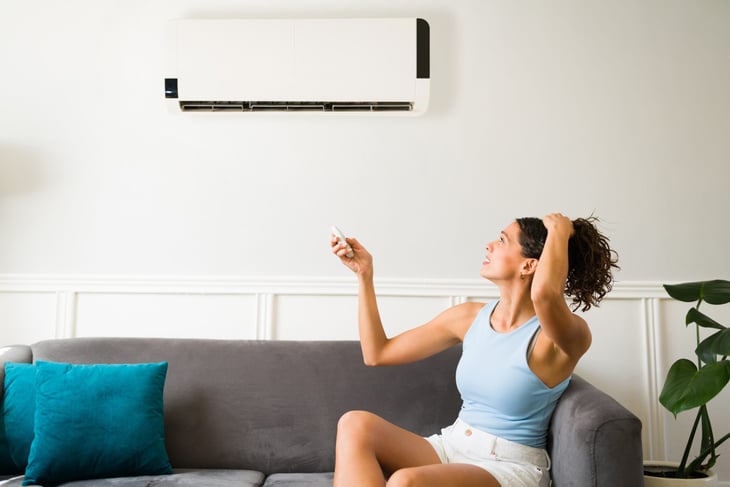 Hot woman adjusting air conditioner
