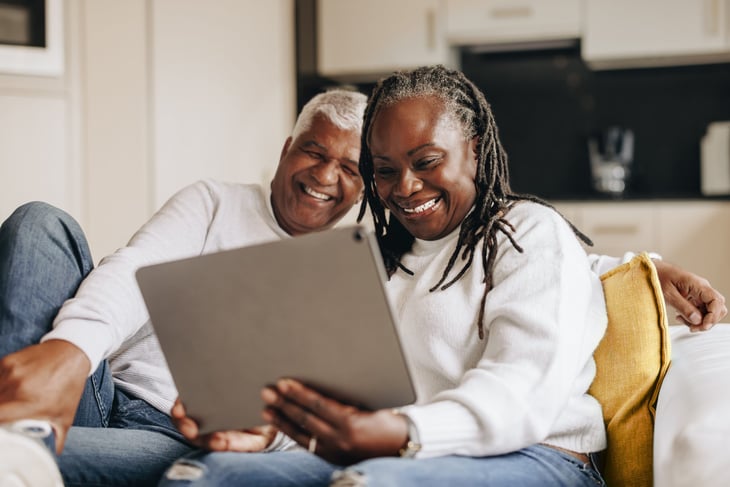 Happy older couple laughing while using a laptop