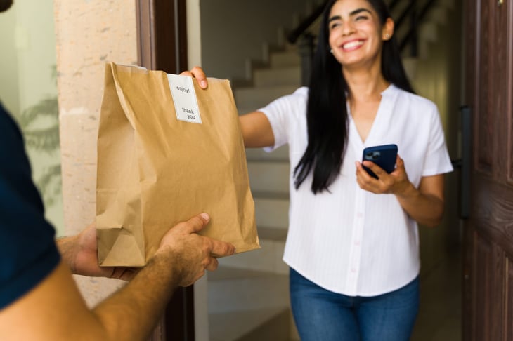 woman receiving a takeout meal bag that was delivered