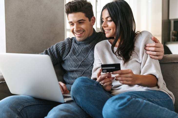 Happy couple making purchases online with a laptop and a credit card