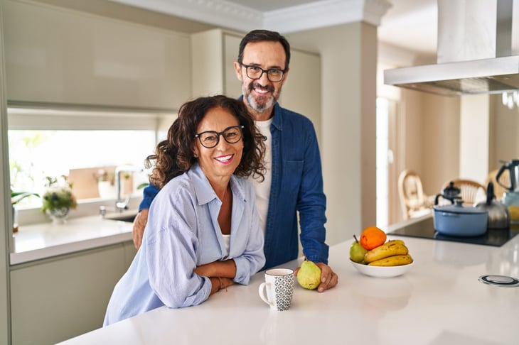 Hispanic couple smiling and holding pears in the kitchen