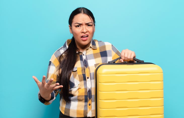 Frustrated woman with luggage angry at the airport baggage policy
