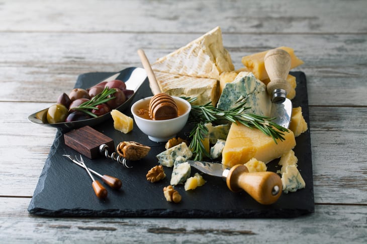cheeses on a board with honey, nuts