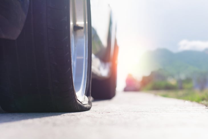 Flat tire on an SUV, with sun shining behind the car
