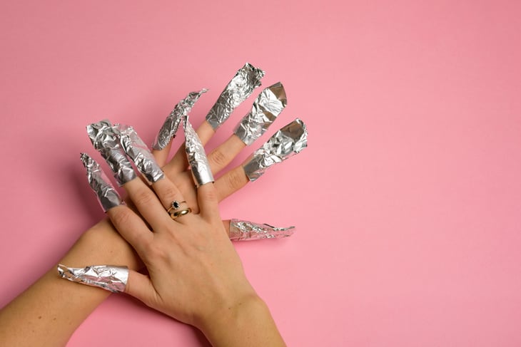 Gel nail polish remover foils on woman's hands