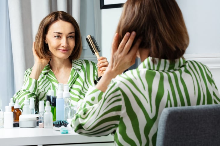 Woman brushing her hair in the mirror.