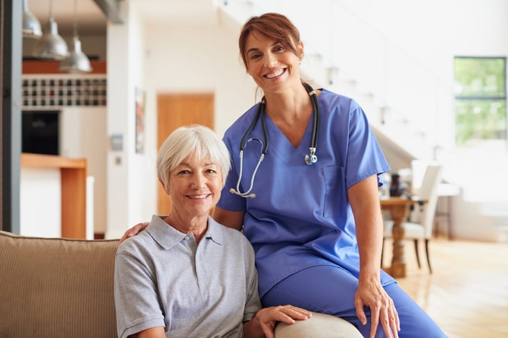 Smiling nurse and happy senior woman patient receiving home health care