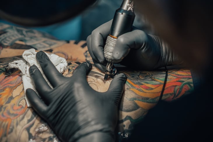 A tattoo artist inks in a design