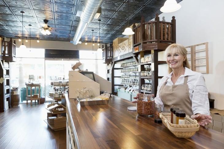 Smiling older woman standing behind the counter at a spice shop.
