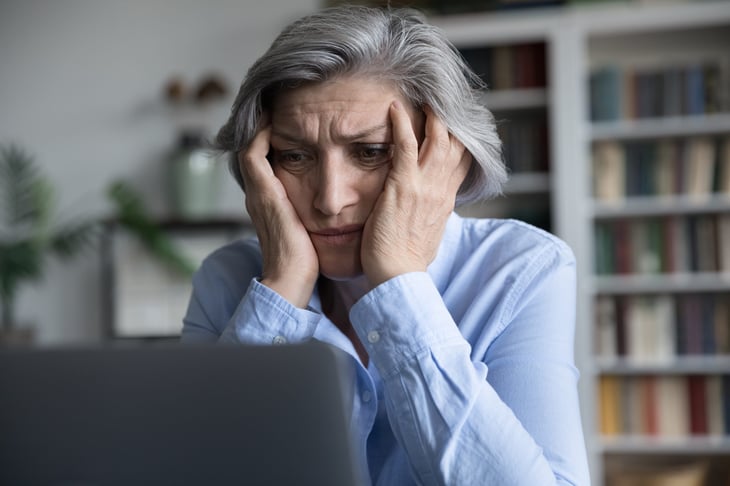 Stressed senior or worried older woman looking at laptop and feeling frustrated, anxious or upset