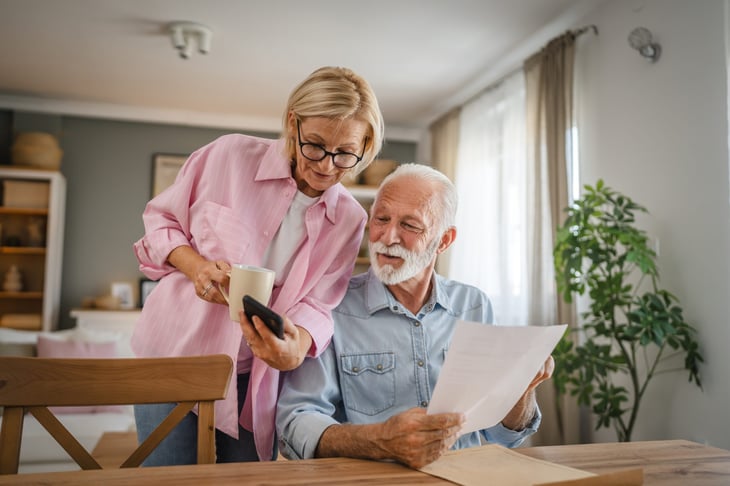 older couple looking at phone and paperwork