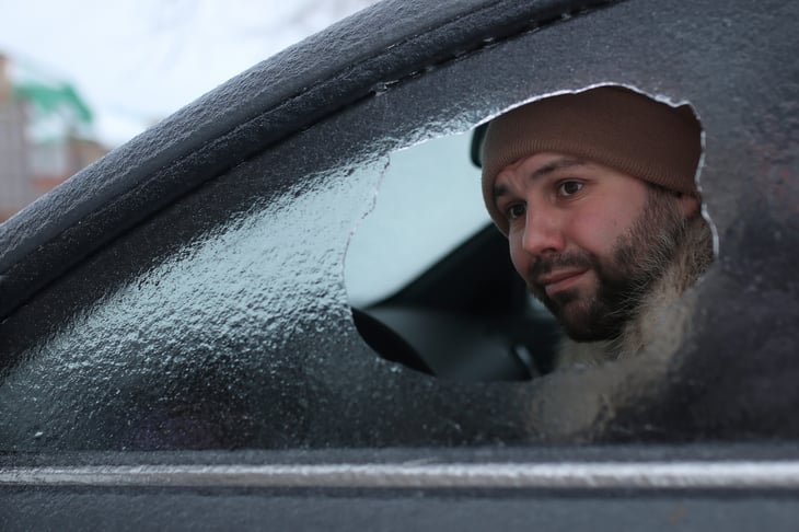 Man looking through an icy window in his car