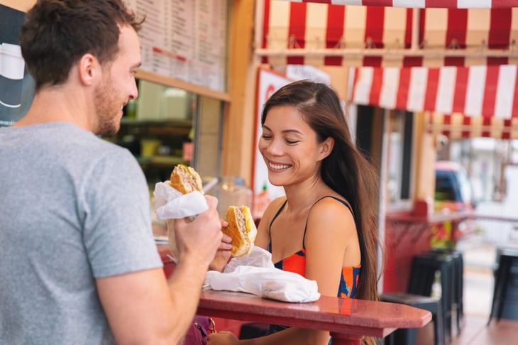 Happy couple eating cuban sandwiches at retro cafe in Florida.