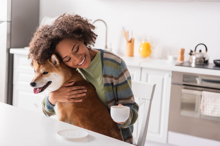 Woman holding her dog while drinking coffee