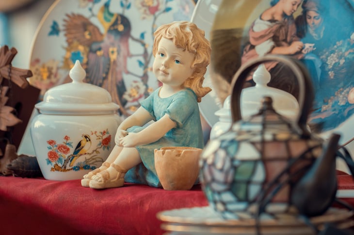 A ceramic figurine and porcelain dishes at a flea market