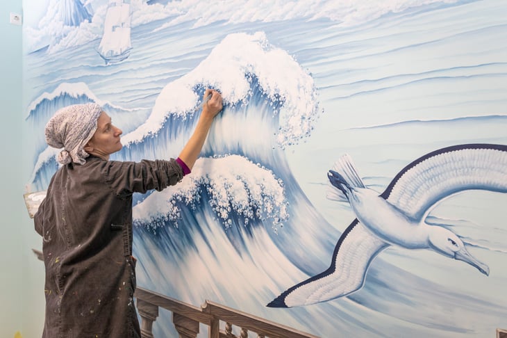 Woman painting a mural in a home