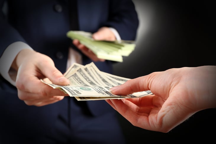 Businessman or government official handing out money in $100 bills