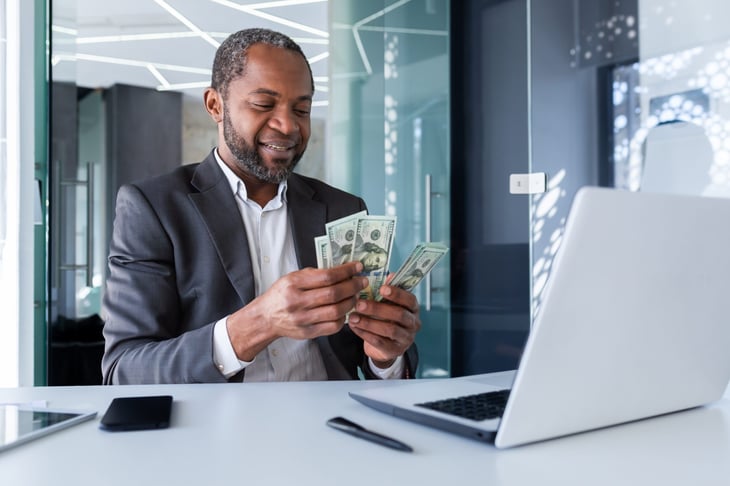 A man counting money in front of a computer