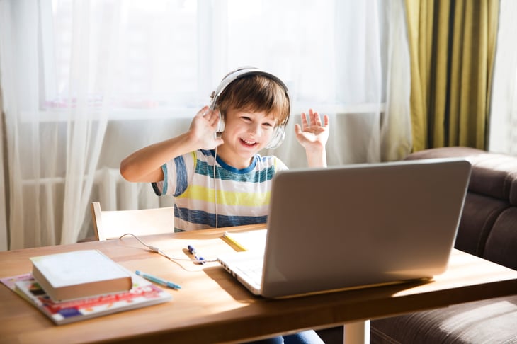 child boy in headphones is using a laptop to study online