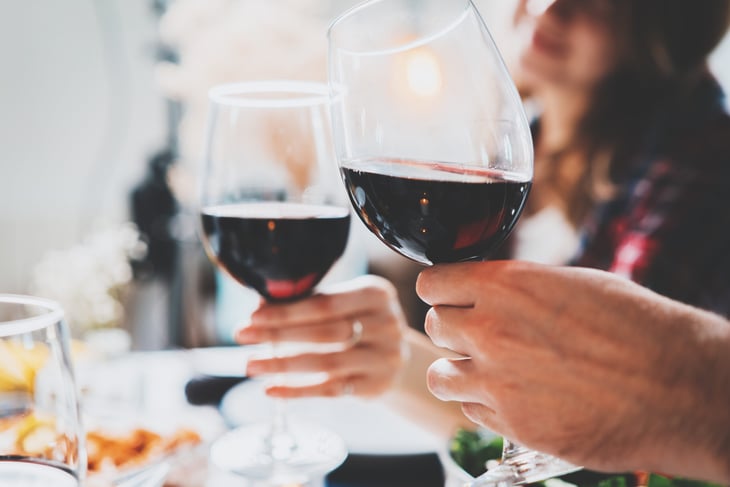couple celebrating and toasting with glasses of red wine