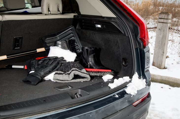 Winter emergency automobile kit with hat, gloves, scarf, and boots in a trunk