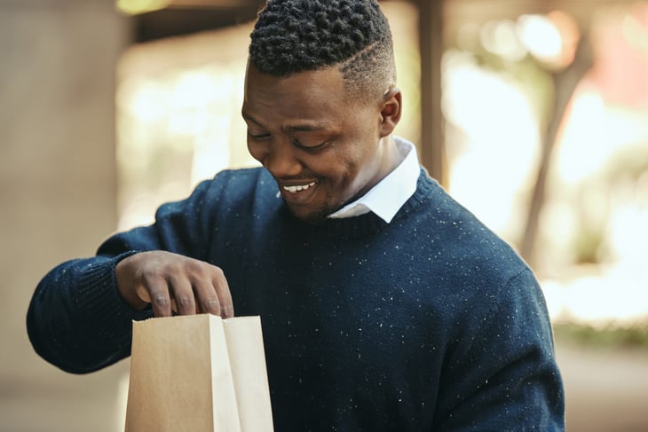 Business man on a lunch break, smiling while opening a brown paper bag