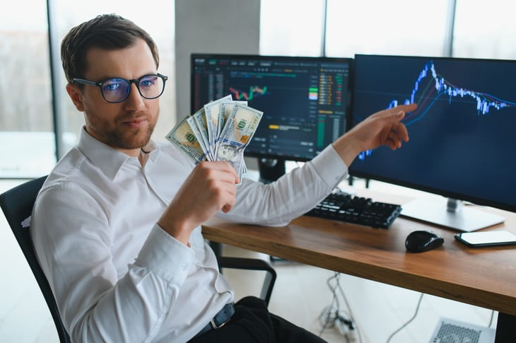 Rich man with money pointing at a stock chart