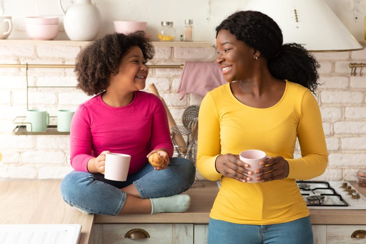 Mom and daughter in a kitchen with mugs of hot chocolate