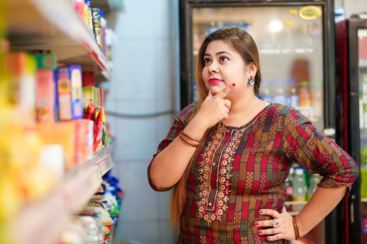 Smiling woman thinking about food at the grocery store and deciding what to purchase