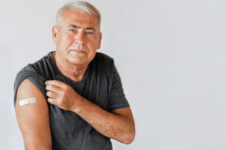 Man with a bandage showing his arm after a flu shot