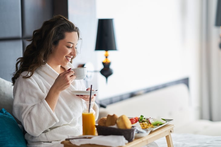 Woman eating breakfast in bed in a hotel