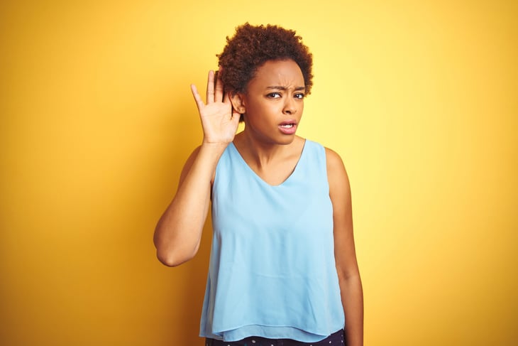 Woman who can't hear with her hand up to her ear.