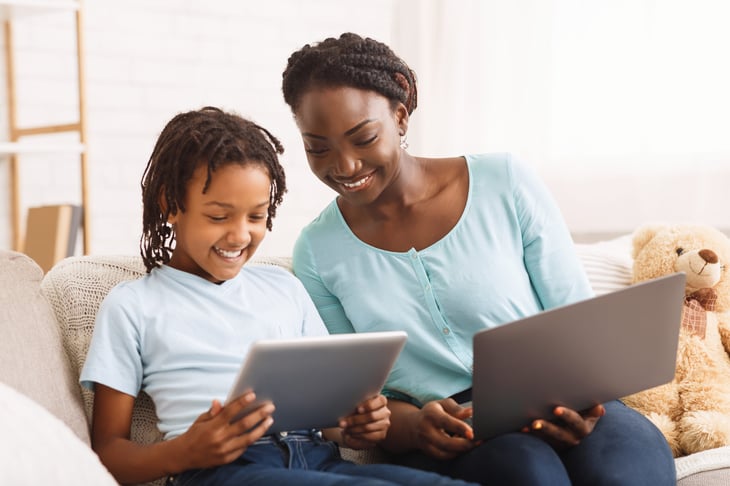 Smiling mother and daughter looking at tablets or iPads together