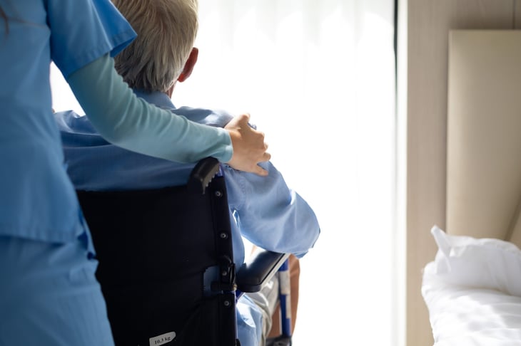 Patient in a wheelchair with a nurse or caregiver in assisted living or nursing home.