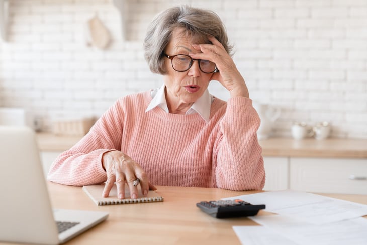 Upset senior looking at documents in her kitchen