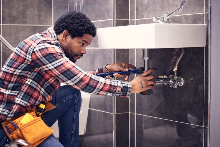 Man installing or repairing a water faucet pipe and fixing the plumbing in the bathroom