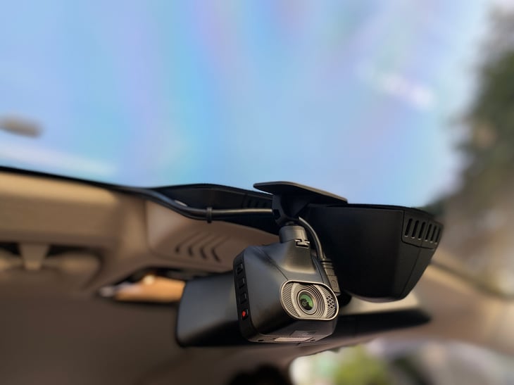 Dash cam closeup photo of installation with camera lens on car dashboard over windshield
