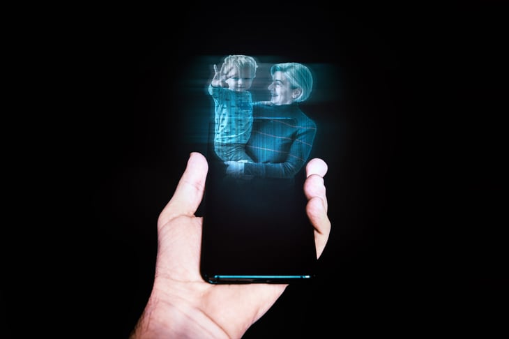 Holographic display on a smartphone with a photo of a grandma and grandchild floating