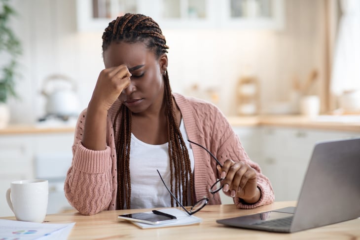 Stressed woman holding her head while working at a laptop