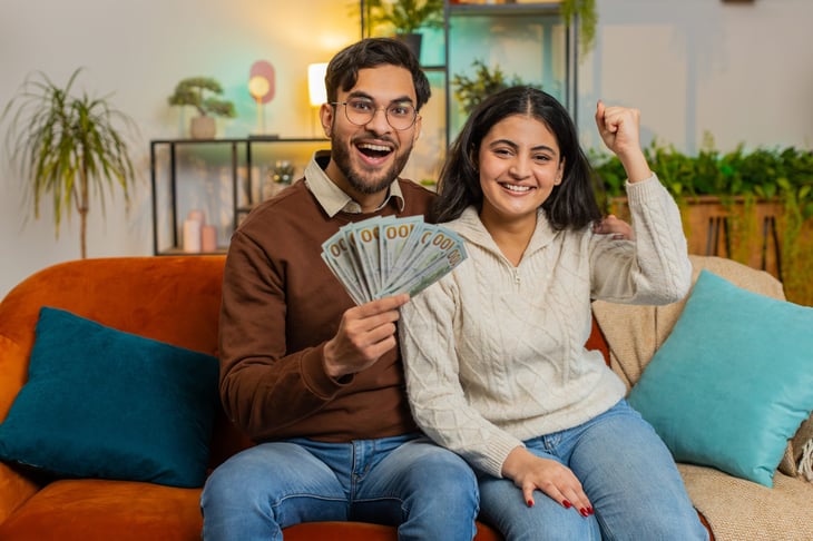 Happy couple at home holding money