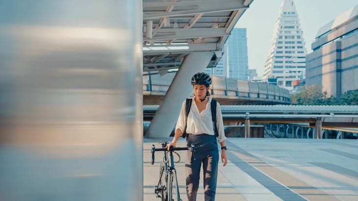 Businesswoman with her bike and helmet at a city plaza. Bike commuting.