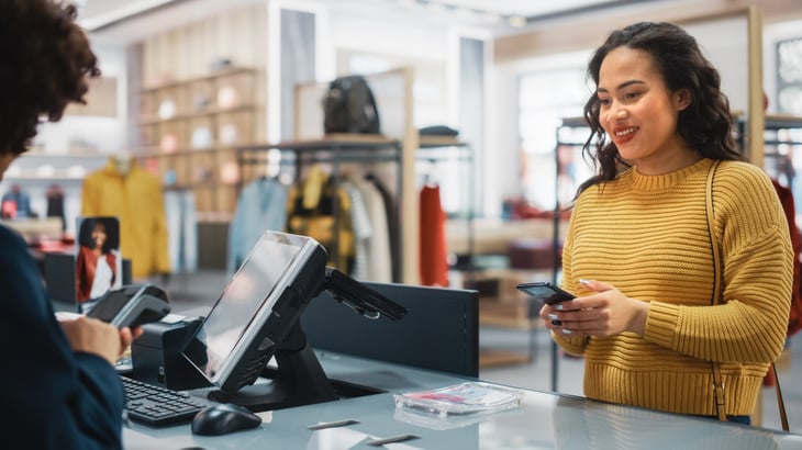 Woman getting a price match with her phone at retailer cashier