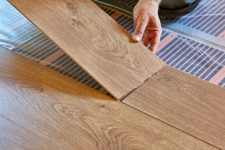 A man laying laminate floor on a heat-insulated floor.