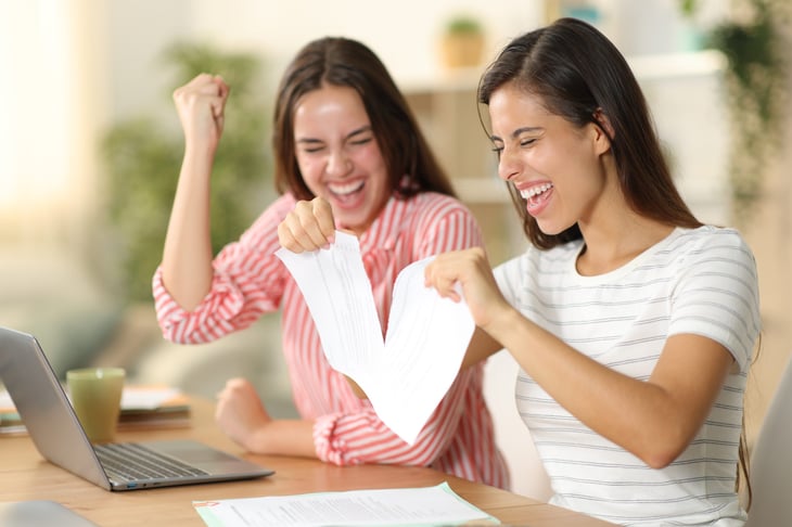 Excited young women ripping up a bill or paid off debt and celebrating being debt-free