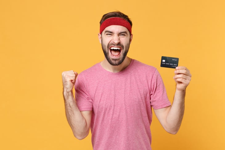 Excited man celebrating in fitness gear and holding a credit card