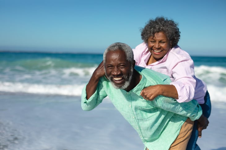 Retired couple laughing and smiling on the beach