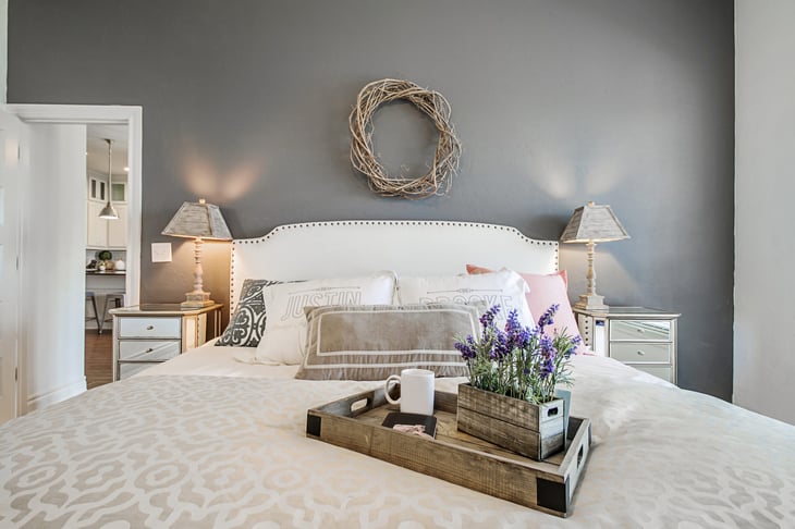 Antique vintage wood tray on a bed in a stylish fashionable bedroom with morning coffee and lavender